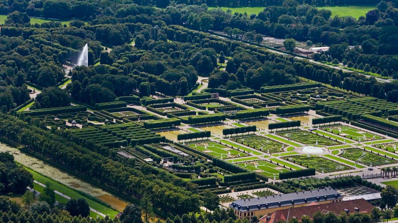 image-hannover-garden Luftaufnahme des Großen Gartens in Herrenhausen mit geometrisch angelegten Beeten, Alleen und Springbrunnen, umgeben von dichten Baumreihen.